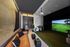 Sophisticated entertainment room with a golf simulator, leather sofa, and modern decor.