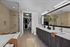 Sophisticated bathroom featuring a glass shower, double sink vanity with modern fixtures, and an entrance to a spacious walk-in closet.