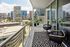 Stylish balcony with modern furniture overlooking a vibrant city skyline.