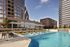 Upscale outdoor pool area with chic lounging furniture in a modern high-rise setting.