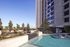 Elegant rooftop pool area with modern seating and lush greenery against a backdrop of towering buildings.