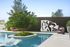 Elegant outdoor pool area featuring modern lounge chairs, greenery, and a stylish wall sculpture.