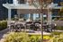 Elegant rooftop patio with modern seating, lush greenery, and a built-in grill against a cityscape.