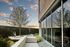 A tranquil outdoor space with modern patio, exercise bike, and lush greenery against a sunset sky.