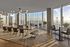 Elegant dining area with panoramic floor-to-ceiling windows and modern furnishings overlooking a cityscape.