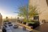 Luxurious rooftop terrace featuring modern seating, lush greenery, and expansive city views at sunset.