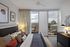 Stylish bedroom featuring a cozy bed, modern decor, and a panoramic city view through large windows.