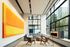 Contemporary living room with large windows, vibrant orange artwork, and chic modern furniture.
