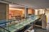 Modern interior space featuring a sleek glass walkway, a cozy wooden dining area, and a comfortable lounge with contemporary seating.