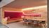 Warm and inviting study nook featuring plush red seating, modern wooden table, and ambient lighting, perfect for cozy gatherings or productive work sessions.