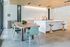 Modern kitchen and dining area with sleek wooden table, pastel chairs, elegant lighting, and a stylish island.