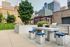 Contemporary rooftop patio with a chic dining set, lush greenery, and a modern grill area set against a stunning cityscape backdrop.