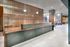 Modern apartment lobby with sleek wooden reception desk, elegant lighting fixtures, and stylish wooden panel accents.