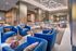 Modern lounge area featuring plush blue armchairs, a stylish dining table, and unique geometric lighting, perfect for relaxation and socializing.