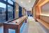 Elegant modern lounge area with floor-to-ceiling windows, cozy seating, and a shuffleboard table for entertainment.