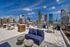 Luxurious rooftop patio offering stunning city skyline views, featuring comfortable seating, dining tables, and a vibrant urban atmosphere.