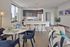 Sleek and modern open-concept kitchen and living area featuring a stylish dining table set, large windows with city views, and elegant decor.