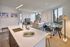 Modern apartment interior with open-concept kitchen, cozy living room, and city views through large windows.
