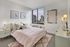 Charming bedroom with city views, stylish decor, cozy bedding, and elegant lighting fixtures.