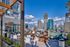 Luxurious rooftop terrace with modern seating and grills, offering stunning views of the city skyline under a clear blue sky.