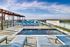 Luxurious rooftop pool area with stylish lounge chairs, panoramic city views, and elegant pergola under a clear blue sky.