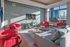 Vibrant living room with modern red armchairs, elegant decor, and breathtaking cityscape views through expansive windows.
