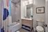 Modern bathroom featuring elegant tile shower, stylish wood vanity, and decorative artwork for a cozy ambiance.