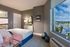 Chic bedroom with elegant d&eacute;cor, featuring a comfortable bed, stylish dresser, and a large window offering a breathtaking marina view.