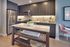 Modern kitchen with sleek gray cabinetry and stainless steel appliances, featuring a stylish island with open shelving and a bowl of green apples.