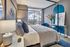 Modern bedroom with a stunning city skyline view, featuring elegant decor, plush bedding, and artistic wall elements.