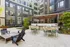 Modern apartment courtyard with stylish outdoor seating, lush greenery, and sleek grill stations for entertaining.