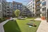 Vibrant courtyard featuring lush green lawn, outdoor seating, and playful string lights, perfect for relaxation and social gatherings.