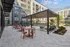 Inviting modern apartment courtyard featuring stylish outdoor seating and lush greenery under a sleek pergola.