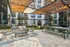 Modern outdoor patio at a stylish apartment complex, featuring comfortable seating, a wooden pergola, and well-maintained greenery.