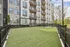 Contemporary apartment building with spacious balconies overlooking a beautifully landscaped green lawn, perfect for relaxation or recreation.