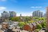 Vibrant urban view featuring modern apartment buildings against a bright blue sky, surrounded by lush green trees and charming row houses.