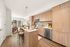Modern open-concept kitchen with sleek wooden cabinetry and a chic living area featuring floor-to-ceiling windows.