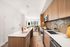 Modern kitchen with sleek wooden cabinetry, elegant island, and open layout leading to a bright living room with city views.