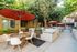 Outdoor courtyard with a modern grill, cozy seating under stylish red umbrellas, and lush greenery