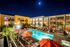 Luxurious apartment complex featuring a sparkling night-lit pool and modern balconies.