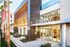 Apartment entrance with sleek architectural design, featuring lush greenery and well-lit glass doors at Runway complex.