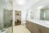 Modern bathroom featuring dual sinks, glass shower, wood cabinetry, and an adjoining walk-in closet