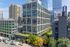 Contemporary urban apartment building with lush rooftop garden, set against a dynamic city skyline.