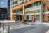 Modern apartment building entrance with glass and wood facade, featuring vibrant abstract sculpture, ideal for urban living.