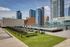 Modern urban rooftop deck featuring a luxurious pool, lounging chairs, and stunning city skyline views.