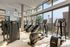 Modern gym in an upscale apartment with state-of-the-art Technogym equipment, large windows showcasing stunning city views.