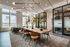 Modern, sunlit conference room with elegant lighting, large wooden table, stylish chairs, and floor-to-ceiling windows offering expansive city views.
