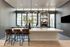 Chic modern kitchen featuring sleek countertops, stylish bar stools, and expansive floor-to-ceiling windows with city views.