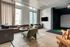 Modern urban living room with sleek leather seating, cozy green chairs, and a large window view, offering luxury and comfort.