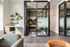 Inviting office space with modern glass partition, cozy seating, and a light-filled interior featuring stylish decor and leafy greenery.